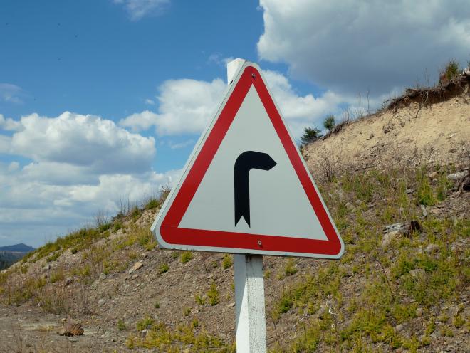 Triangular road sign showing a turn to the right ahead